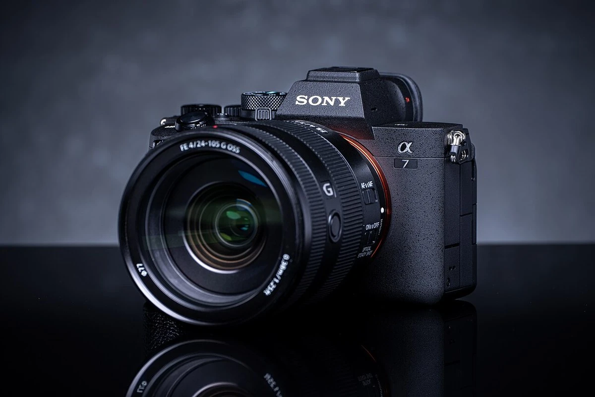 Камера Sony Alpha 7 IV на чорному глянцевому столі зі штатним зум-об'єктивом і помаранчевим кільцем байонета